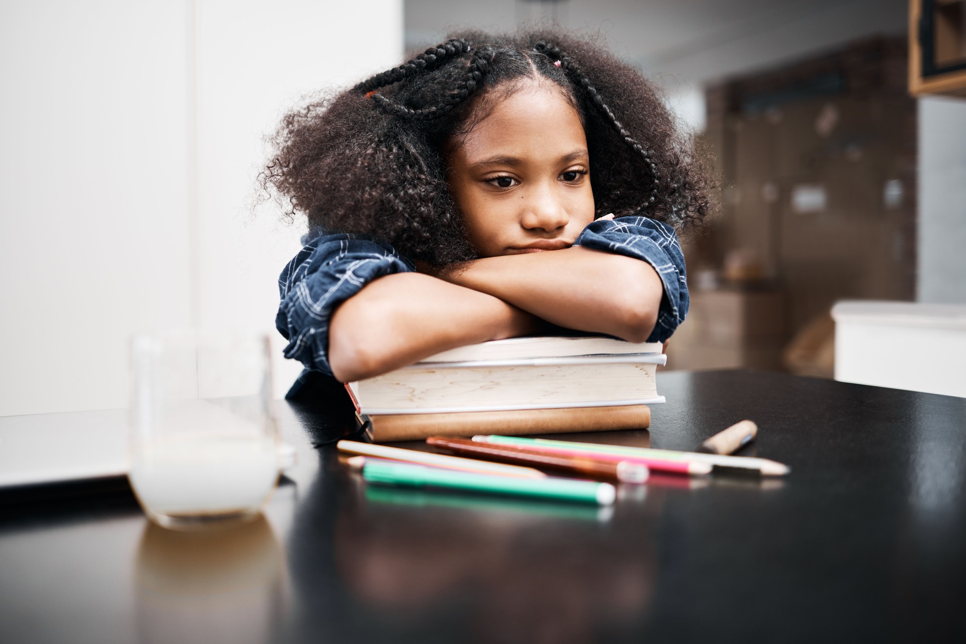 Shot of a young girl looking unhappy while doing a school assignment at home